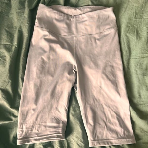 Ljusgrå cykelshorts med hög midja - Snygga ljusgrå cykelshorts med hög midja och tight passform. Perfekta för träning eller när du vill ha en sportig look. Tillverkade i stretchigt syntetmaterial som sitter skönt och följer kroppen.