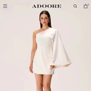 Slutsåld ny ADOORE Vit one shoulder klänning  - Oanvänd , prislapp kvar. Superfin vit kortklänning från Adoore. Slutsåld på hemsidan. Storlek 46 (obs liten i strl). Dragkedjan går inte att dra ner helt därför säljer jag den (men klänningen går att sätta på ändå så länge man passar i storleken). Nypris 1395kr, säljer för 549kr
