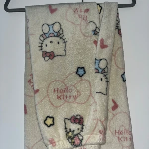 Hello Kitty fleecebyxor med mönster - Supermjuka fleecebyxor med Hello Kitty-motiv, hjärtan och stjärnor i pastellfärger. Byxorna är ljusa med rosa, blå och gula detaljer och har en mysig känsla – perfekta för chill hemma eller sleepovers.💞💞