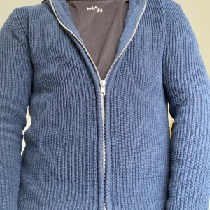 Mörkblå stickad kofta med dragkedja - Säljer en mörkblå stickad kofta med hel dragkedja framtill. Koftan har ribbad struktur och lång ärm, perfekt för lager-på-lager. Enkel och stilren design som funkar till det mesta. Passar dig som gillar en klassisk look med modern touch.