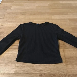 Svart ribbad långärmad tröja SHEIN - En svart långärmad tröja från SHEIN i storlek M. Tröjan är ribbad med rund halsringning och har en enkel, stilren design som är lätt att matcha. Perfekt för lager-på-lager och funkar året runt.