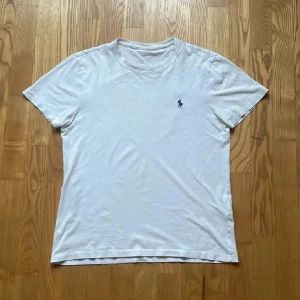 Vit t-shirt från Ralph Lauren - Vit t-shirt från Ralph Lauren med klassisk passform och liten broderad logga på bröstet. T-shirten har rund halsringning och är tillverkad i mjuk bomull, perfekt för en clean och enkel stil. T-shorten är knappt använd och köpes i affären för cirka 1 vecka sen.