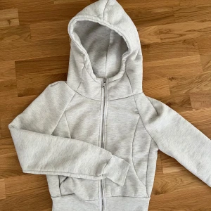 Ljusgrå hoodiejacka från SHEIN XS - Ljusgrå hoodiejacka från SHEIN i storlek XS. Jackan har dragkedja framtill, huva och ribbade muddar vid ärmslut och nederkant. Mjuk insida och enkel, clean look som passar till allt. NY, utan prislapp då det inte kommer prislapp mer.