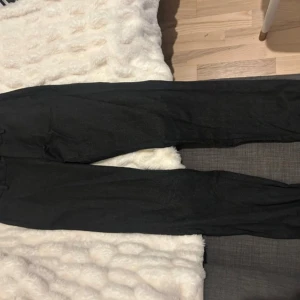 Grå kostymbyxor från Massimo Dutti - Snygga mörkgrå kostymbyxor från Massimo Dutti i italienskt tyg. Byxorna har elastisk midja, raka ben och klassisk look. Perfekta för dig som vill ha en dressad men ändå chill stil. Jogger fit för extra komfort.