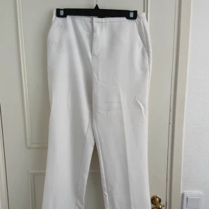 KÖP FRÅN MIN VINTED - Snygga vita kostymbyxor med raka ben och diskreta fickor i sidorna. Klassisk look med enkel stängning framtill och stilren passform. Perfekta för en clean och fräsch outfit.