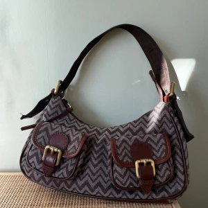 Sport missoni vintage shoulder bag - Rare vintage Missoni Sport bag – no longer in production and nearly impossible to find today. Features the iconic zigzag pattern with genuine brown leather details and gold-tone buckles.  Model name: Borsa missoni in Pelle altoro In perfect condition with barely no signs of wear – only some minor scratches at the bottom leather (please ask for photo)  A timeless and collectible piece 🤎  Approx measurements on the last two pictures.  SELLING ON VINTED FOR 1000SEK
