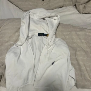 Vit hoodie med dragkedja från Polo Ralph Lauren - Yes jag säljer nu en klassisk vit hoodie från Polo Ralph Lauren med dragkedja och huva. Tröjan har två fickor framtill och den ikoniska loggan broderad på bröstet. Perfekt för en avslappnad och stilren look. Då den har blivit för liten för mig har inget pris en men en ny går för 2300 priset diskuteras, hör av er om du vill ha bilder
