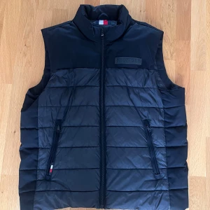 Väst från Tommy hilfiger - Väst från Tommy hilfiger, Bra skick förutom en liten fläck på ryggen och på insidan vid bröstet. Köpt för 2000kr för ca 1.5 år sedan 