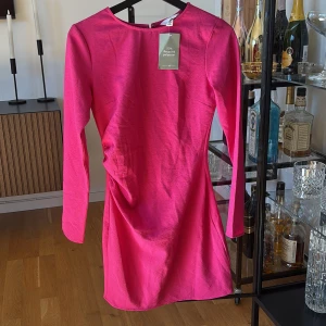 Rosa långärmad kortklänning H&M - Snygg rosa kortklänning från H&M med lång ärm och rund halsringning. Aldrig använd. 