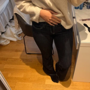 Mörkblå bootcut jeans med kontrastsömmar - Snygga mörkblå jeans med bootcut passform och tydliga kontrastsömmar. Klassisk femficksmodell med gylf och knapp framtill. Jeansen har en låg midja och är tillverkade i ett stretchigt denimtyg som sitter riktigt bra.