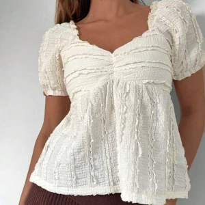 Beige blus med volang och puffärm - Supersöt vit blus med korta puffärmar och volangdetaljer. Storlek S och sitter perfekt på, är ej tajt. Skriv för egna bilder!