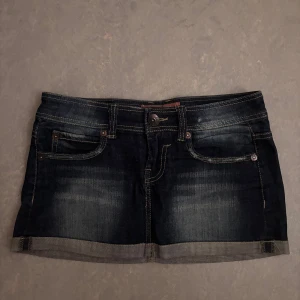 Mörk jeanskjol med fickor - Mörkblå jeanskjol i storlek 36. Köpt i spanien. Aldrig använd men har använt utseende i färgen.