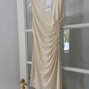 Kort festklänning - Helt oanvänd klänning från Zara. Den är krämvit i färgen och har dragkedja i ryggen. 