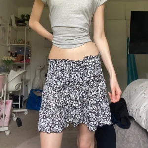 Blommig volangkjol - Supersöt kort kjol med svart botten och vita blommor. Kjolen har flera volanger och resår i midjan för en bekväm passform. Perfekt för vår och sommar, och ger en riktigt fräsch vibe till outfiten😻Kan ha som low, mid & high waist!! Passar XS, kanske S eftersom den är stretchig💋!!OBS!! kolla sista bilden! I cirkeln är kjolens material hårt och stelt, för att jag har råkat spillt något som torkat där. Men det är ingen som syns, bara något man känner😔🫶🏻