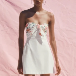 Vit kort klänning med blommig rosett - Säljer denna supersöta slutsålda klänning från zara i storlek xs! Klänningen är aldrig använd och har lappen kvar! 