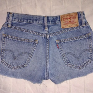 Levis 505 blå jeansshorts - vintage cut off shorts  - Skitsnygga blå avklippta jeans 505 från Levis. Klassisk femficksdesign, råa kanter nertill och Levi's-patch bak. Perfekta för sommaren med sin avslappnade vibe och snygga passform. Bälteshällor och knappgylf. Ikonisk denimstil som aldrig går ur tiden. Storlek midja: 29.