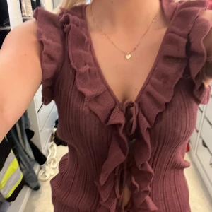 Vinröd ribbad blus med volang - Supersöt vinröd blus med volangdetaljer längs v-ringningen och framtill. Toppen är ribbad och har knyt framtill. Från Zara, hör av er vid frågor🥰