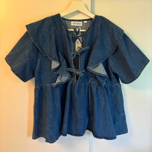 Jeansblus med volang från Carin Wester - Säljer denna superfina denimblusen från Carin Wester, den är aldrig använd o har lappen kvar☺️Nypris: 699 kr
