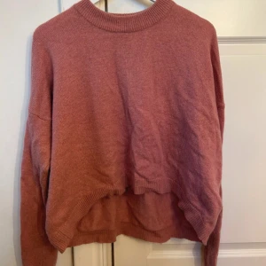 Rosa stickad croppad tröja - Mysig rosa stickad tröja med croppad passform och längre baktill. Tröjan har rund halsringning och långa ärmar. Perfekt för lager-på-lager och chill dagar. Från hm