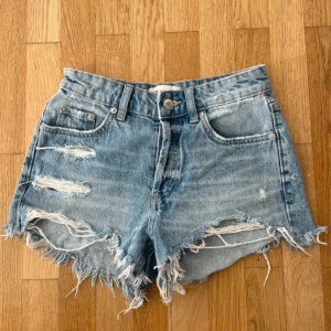 Jeansshorts från Zara - Snygga blå jeansshorts från Zara med slitna detaljer framtill. Perfekta för sommaren!