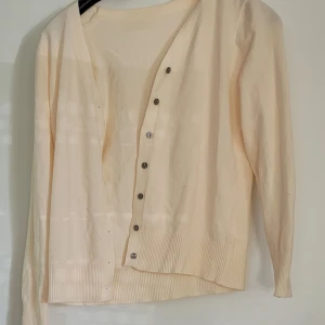 Beige kofta med knappar - Ljusbeige kofta i mjukt material med långa ärmar och v-ringning i storlek m. Känns mer som en s/xs enligt mig. Vet ej märke