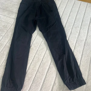 Svarta mjukisbyxor från H&M - Svarta mjukisbyxor från H&M med resår och snörning i midjan. Byxorna har raka ben med resår vid bensluten och är tillverkade i mjuk bomull. Perfekta för en chill och avslappnad stil.
