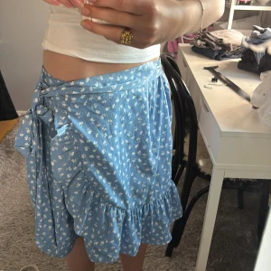 as gullig sommar kjol!🩵 - Supersöt blå somrig omlottkjol med vita småblommor, volangkant och knyt i midjan. 