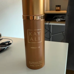 Kayali Vanilla | 28 Body Spray - Kayali Vanilla | 28 All Over Body Spray i en lyxig bronsfärgad metallflaska med guldiga detaljer. Doften är söt och varm med tydlig vaniljton, perfekt för dig som älskar gourmanddofter. Flaskan rymmer 125 ml och har en stilren, modern design. Ungefär lite mindre en halva kvar!