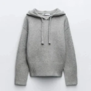 Zara stickad tröja   - Snygg grå stickad hoodie med huva och snörning framtill. Tröjan har långa ärmar och bred ribbad kant vid midjan och ärmsluten. Perfekt för dig som gillar en chill och enkel stil med lite extra mysfaktor.