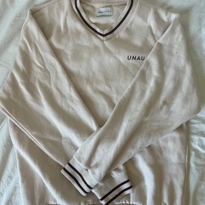 Beige Unauthorized tröja med v-ringning - Snygg beige tröja från Unauthorized med v-ringad hals och mörkbruna ränder på krage och muddar. Bra kondition- Storlek S