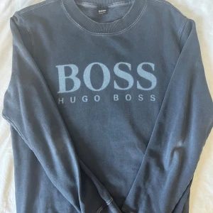 Mörkgrå sweatshirt från Hugo Boss - Snygg mörkgrå sweatshirt från Hugo Boss med stort BOSS-tryck på bröstet. Bra kondition - Storlek M