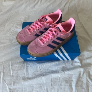 Adidas Originals Gazelle Bold Rosa Sneakers - Säljer ett par Adidas Gazelle sneakers i en snygg rosa färg med mörkblå ränder och detaljer. Använd max två gånger och fortfarande i bra skick! Storlek 42