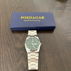 Grön POEDAGAR klocka med länkarmband - Snygg klocka från POEDAGAR med grönt urtavla och dag/datumvisning. Klockan har ett stilrent silverfärgat länkarmband i metall och en rund boett med minimalistisk design. Perfekt för dig som gillar klassisk stil med en modern twist.