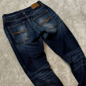 Nudie grim tim jeans - Tja! Säljer dessa schyssta blå Nudie ”Grim Tim” jeansen med fet tvätt! Jeansen är i bra skick, inga defekter. Size 34/32. Skriv vid funderingar!