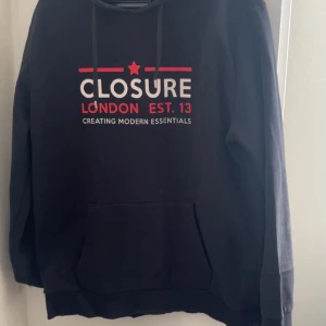 Svart hoodie Closure London XL - Svart hoodie från Closure London i storlek XL. Tröjan har huva med snörning. Lite av tyget runt snöret har gott sönder men inget som egentligen stör funktionen. Hundar finns i hemmet!!