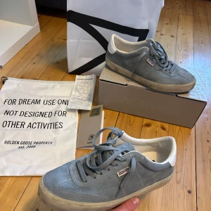 Golden Goose Soul-Star ljusblåa sneakers - Golden Goose Soul-Star sneakers i ljusblå mocka med vita detaljer och platt sula. Snygg retrostil med rund tå, snörning och logotyp på sidan. Insidan är vit och sulan har ett klassiskt fiskbensmönster. Perfekt för dig som gillar streetwear och italiensk design. Köpta på NK Ny pris 4750kr kvitto finns. Skick 9/10 andvända 5 gånger 