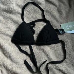 Svart bikiniöverdel med snörning - Supersnygg helt ny svart bikiniöverdel från H&M med klassisk triangelmodell och knyt i både nacke och rygg. Materialet är mjukt och gjort av 100% återvunnen polyester. Pris kan självklart diskuteras 🫶