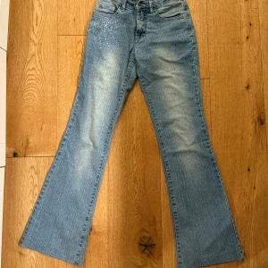 Low waist Blå bootcut jeans  - Snygga blå bootcut jeans med cool strassdekor på ena fickan. Perfekta för dig som vill sticka ut lite extra med detaljer. Perfect for girlies av 166cm or shorter