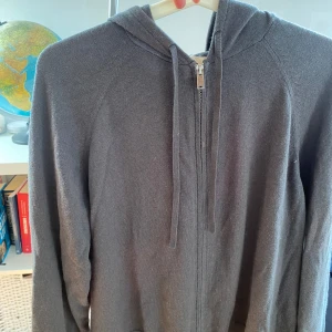 Grå hoodie i kashmirblandning - Mjuk och stilren grå hoodie från H&M i kashmirblandning. Tröjan har dragkedja framtill, huva med snörning och långa ärmar. Perfekt för dig som gillar chill och enkel stil med lite lyxig känsla. Passar dig som vill ha en hoodie som är både bekväm och snygg.