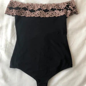 Svart intimissimi offshoulder body  - Säljer en svart offshoulder topp med bred, spets upptill. Bodyn är figurnära och materialet är mjukt och stretchigt, perfekt för att styla med jeans eller kjol. Det står storlek M men passar mig som vanligtvis har S också 😇 Finns ett liiiitet igensytt hål men inget som syns (se sista bilden) 💕 går ej att få tag på i butik längre!! 💖💖💖