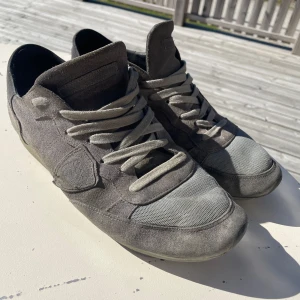 Phellipe model - Snygga grå sneakers med ovandel i mocka och mesh, samt matchande grå skosnören. Skorna har en platt sula och rund tå, vilket ger en clean och stilren vibe. Perfekta för dig som gillar neutrala färger och vill ha ett par skor som funkar till det mesta.