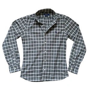 Ralph Lauren Skjorta - Säljer nu denna sjukt snygga Ralph Lauren button-down skjortan! Skick 9/10, den är uppsydd så kan hända att den påsar sig i ryggen på vissa. Inget som man dock tänker på. Mått: bröstvidd: 50cm, armlängd fr axel: 65cm längd fr axel: 61cm. Om du undrar något är det bara att fråga! OBS ser grå ut på första två bilderna men den riktiga färgen syns i de andra bilderna