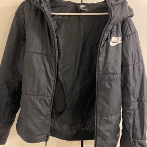 Svart pufferjacka från Nike - Svart pufferjacka från Nike med huva 