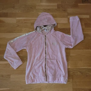 Kofta - Ljusrosa huvtröja från Lindex i storlek 158/164. Den är använd 2-3 gånger och är därför I jättebra skick. Det finns tryck både på fram och baksidan. Kan fraktas!