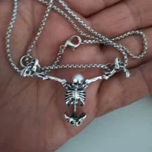  Helt ny Silvrigt halsband med skelettberlock -  Helt ny Unikt halsband i silverfärgad metall med en cool skelettberlock som hänger i kedjan. Skelettet har utsträckta armar och detaljerad design som ger en edgy vibe. Perfekt för dig som gillar statement-smycken och vill sticka ut med din stil.