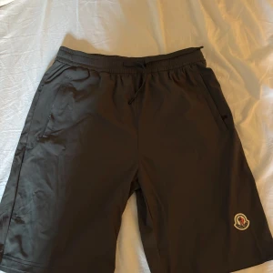 Svarta shorts från Moncler  - Svarta shorts från Moncler i storlek XL med elastisk midja och snörning. Snyggt Moncler-märke på benet, praktiska fickor med dragkedja och stilren design.  Fantastiskt skick aldrig använda! Passar för L 