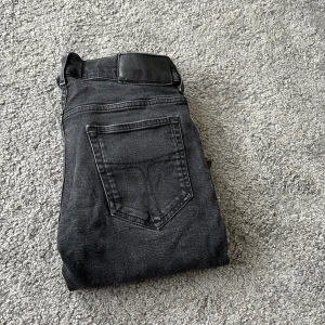 Slim svarta jeans från tiger of Sweden  - Säljer ett par svarta slim fit jeans från tiger of Sweden Jeansen har klassisk femficksdesign, snyggt tiger of Sweden läderpatch Dock är den lite sliten bak, jeansen har smal passform som sitter schysst längs benen.  med mjukt och slitstarkt denimtyg.