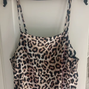 Leopardmönstrad linnetopp från Lindex - Säljer en snygg leopardmönstrad linnetopp från Lindex med tunna axelband. Den har svarta och vita ränder längst ner. Är tillverkad i glansigt syntetmaterial som känns mjukt mot huden. Toppen är som ny och har ej använts många gånger💕