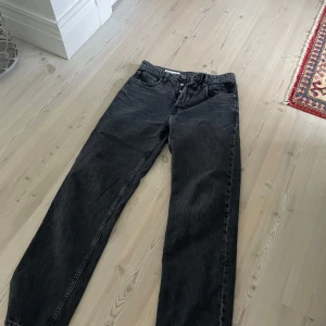 Svarta jeansbyxor från Zara loose  - Säljer ett par svarta jeansbyxor från Zara i klassisk femficksmodell. Byxorna har normal passform och raka ben, perfekt för en stilren look. Storlek w30, tillverkade i ett slitstarkt jeanstyg.