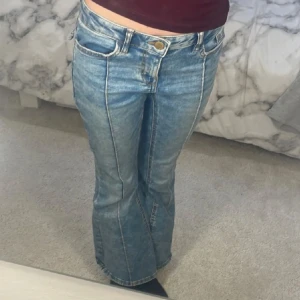 Blå bootcut jeans från Lindex - Säljer ett par ljusblå bootcut jeans från Lindex, modell Freja. Jeansen har klassisk femficksdesign, markerade sömmar framtill och normal passform upptill som går ut i ett bootcut-snitt nertill. Perfekta för dig som gillar retrostil!